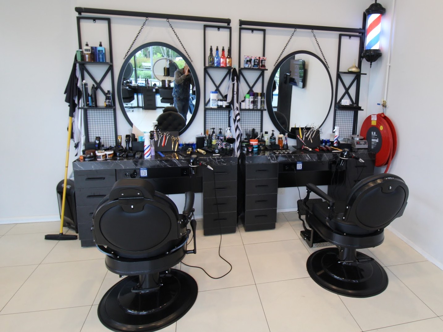 Twee kapperstoelen voor ronde spiegels met een barberpole in de salon